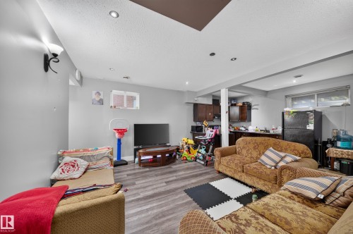 Recessed lighting, wood-finish flooring, and a kitchen area with dark cabinetry - 6904 18 Avenue Sw, Edmonton, AB 