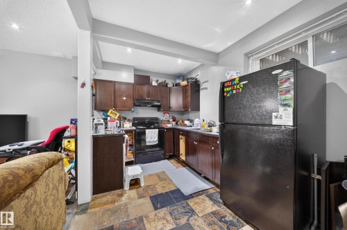 Kitchen featuring dark wood-finish cabinetry, black appliances, recessed lighting, and multi-tone tile flooring - 6904 18 Avenue Sw, Edmonton, AB 