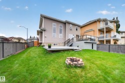 Expansive rear yard with a tiered composite deck, glass panel railing, and integrated storage area - 