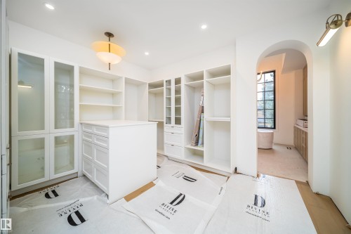 White custom built-in cabinetry with glass-front accents, central island with drawer storage, recessed lighting, and an arched doorway - 10414 134 Street Nw, Edmonton, AB 
