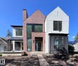 Modern exterior featuring brick and stucco finishes, black-framed windows, a prominent brick chimney, and a metal-roofed entrance canopy - 10414 134 Street Nw, Edmonton, AB 
