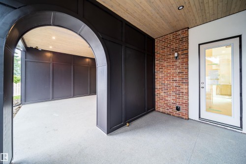 Covered outdoor space featuring a wood-finish ceiling, exposed brick wall, and an arched entryway - 10414 134 Street Nw, Edmonton, AB 