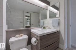 Modern bathroom featuring a floating vanity with rectangular sink, white quartz countertop, and polished chrome fixtures - 