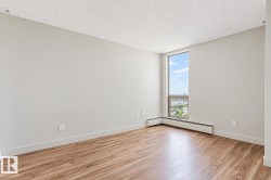Wood-finish flooring, light grey painted walls, window with aluminum frame, white baseboard heating, and textured ceiling - 