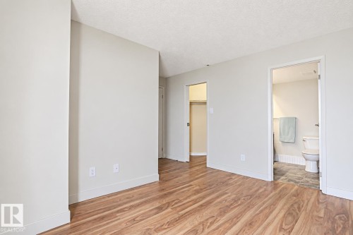 Bright, open bedroom with wood-finish flooring throughout, white walls, and multiple closet spaces - #2005 10149 Saskatchewan Dr Nw, Edmonton, AB 
