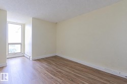 Expansive room with wood-finish flooring, light-toned walls, and a large window - 