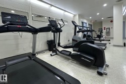 Fitness center featuring multiple exercise machines, mirrored walls, and recessed lighting - 