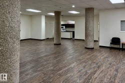 Open concept room with wood-finish flooring, exposed aggregate columns, recessed lighting, and a white ceiling - 
