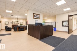 Lobby area featuring neutral-toned flooring, recessed lighting, and a dark wood-finish reception desk - 