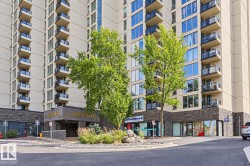 High-rise building with a stone-clad base and multiple levels of individual balconies featuring glass railings - 