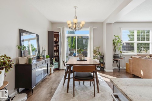 Dining area featuring wood-finish flooring, a contemporary chandelier, and a built-in storage cabinet - 3204 Abbott Crescent Sw, Edmonton, AB - Indoor Photo Showing Other Room
