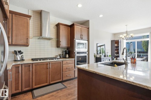 Kitchen featuring light-toned wood cabinetry, stainless steel appliances, and a tiled backsplash - 3204 Abbott Crescent Sw, Edmonton, AB - Indoor Photo Showing Kitchen With Double Sink
