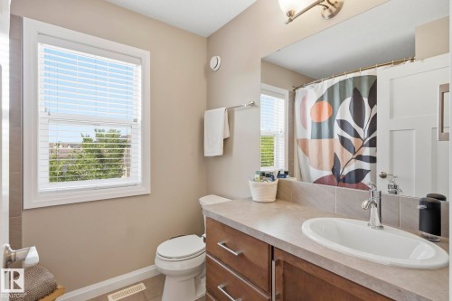 Bathroom featuring a wood-finish vanity with an integrated sink, a large mirror, and tiled flooring - 3204 Abbott Crescent Sw, Edmonton, AB - Indoor Photo Showing Bathroom