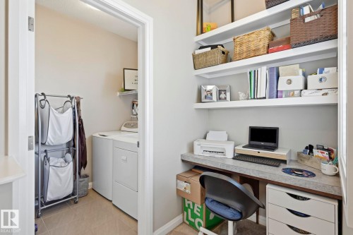 Dedicated workspace featuring a built-in desk with a stone-finish countertop and three floating shelves - 3204 Abbott Crescent Sw, Edmonton, AB - Indoor Photo Showing Laundry Room