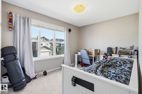Bright bedroom featuring a large window with white trim, light gray carpet, and neutral wall paint - 3204 Abbott Crescent Sw, Edmonton, AB - Indoor