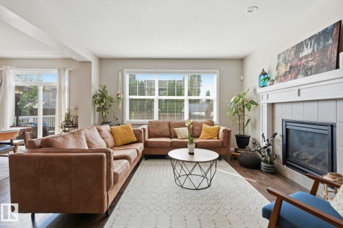 Bright living area featuring a fireplace with a white mantel and tile surround - 3204 Abbott Crescent Sw, Edmonton, AB - Indoor Photo Showing Living Room With Fireplace