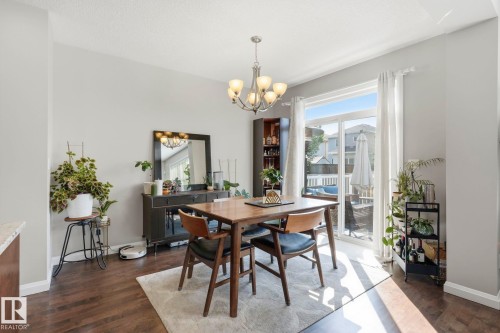 Dining area featuring wood-finish flooring, a contemporary chandelier, and a sliding glass door providing outdoor access - 3204 Abbott Crescent Sw, Edmonton, AB - Indoor Photo Showing Dining Room