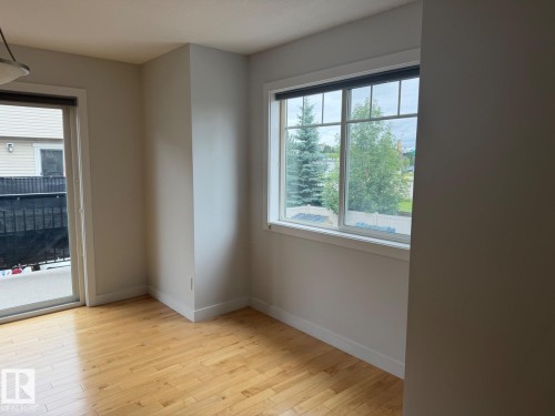 Wood-finish flooring, white trim, sliding glass door, and a multi-pane window - #85 9535 217 St Nw, Edmonton, AB 