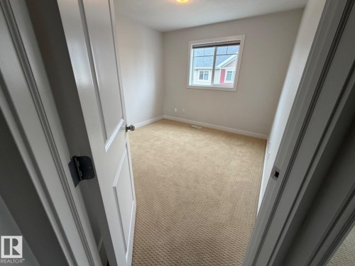 Neutral wall paint, carpet flooring, a window with trim, and a ceiling light fixture - #85 9535 217 St Nw, Edmonton, AB 