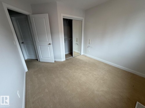 Neutral tone wall paint, carpeted flooring, white trim, solid core doors, mirrored closet doors - #85 9535 217 St Nw, Edmonton, AB 