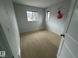 Carpeted room featuring multiple windows, white trim, and a paneled door - 