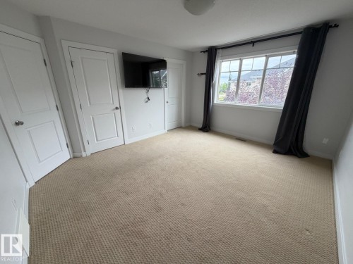 Carpeted room featuring multiple panel doors and a multi-pane window - #85 9535 217 St Nw, Edmonton, AB 
