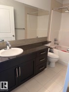 Vanity with integrated sink, dark cabinetry, and stone-finish countertop - 