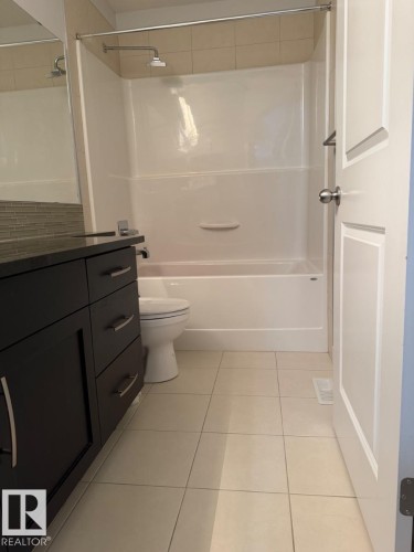 Modern vanity with dark wood-finish cabinetry, chrome hardware, and a dark countertop - #85 9535 217 St Nw, Edmonton, AB 