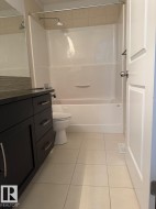 Modern vanity with dark wood-finish cabinetry, chrome hardware, and a dark countertop - 