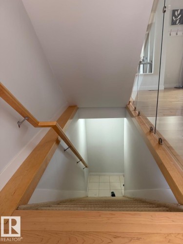 Staircase featuring wood railings, glass paneling, and carpeted treads - #85 9535 217 St Nw, Edmonton, AB 