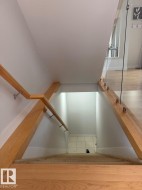 Staircase featuring wood railings, glass paneling, and carpeted treads - 