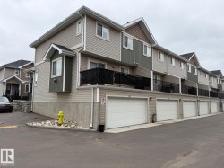 Multi-level townhome featuring horizontal siding, a bay window, a second-story balcony with black railings, and an attached garage with a white door - 