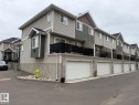 Multi-level townhome featuring horizontal siding, a bay window, a second-story balcony with black railings, and an attached garage with a white door - #85 9535 217 St Nw, Edmonton, AB 