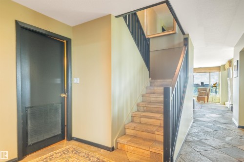 Tiled flooring, staircase with wood handrail, and large windows - #1202 10010 119 St Nw, Edmonton, AB 