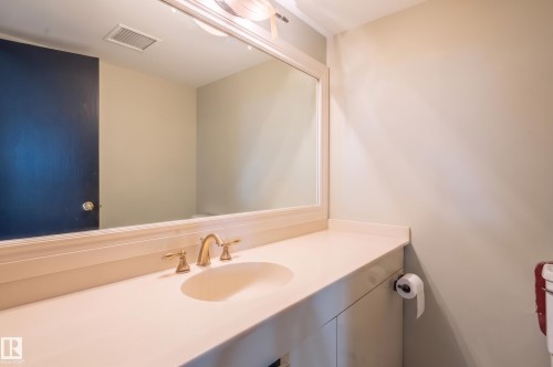Vanity with an integrated sink, polished brass faucet, and an overhead vanity light fixture - #1202 10010 119 St Nw, Edmonton, AB 