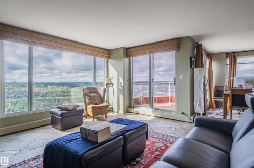 Expansive floor-to-ceiling windows, natural stone tile flooring, direct access to a private balcony, and ample natural light - #1202 10010 119 St Nw, Edmonton, AB 