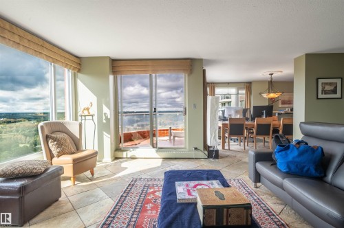 Expansive floor-to-ceiling windows, direct balcony access, tile flooring, and a dining area with a chandelier - #1202 10010 119 St Nw, Edmonton, AB 