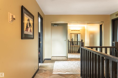 Hallway featuring slate flooring, painted walls, and dark wood railings - #1202 10010 119 St Nw, Edmonton, AB 