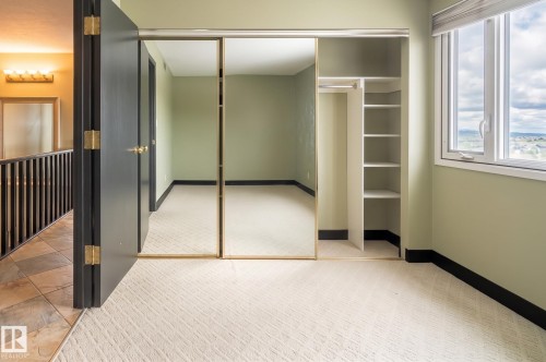 Expansive window, built-in shelving, carpet flooring, mirrored closet doors, and a tiled hallway - #1202 10010 119 St Nw, Edmonton, AB 