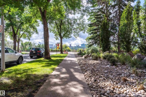 Paved sidewalk with mature trees and a gravel landscape feature - #1202 10010 119 St Nw, Edmonton, AB 
