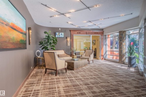 Expansive common area featuring a patterned carpet, track lighting, a curved accent wall, and floor-to-ceiling windows - #1202 10010 119 St Nw, Edmonton, AB 