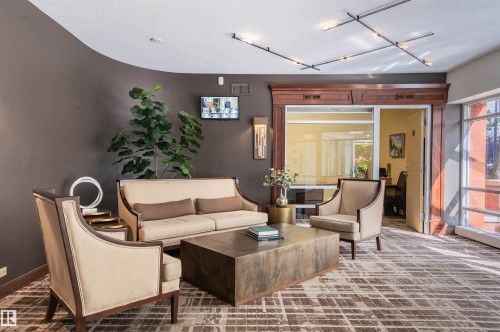 Textured wall covering with a curved accent, glass-paneled entry, full-height windows, and recessed ceiling lighting - #1202 10010 119 St Nw, Edmonton, AB 