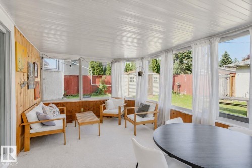 Sunroom with wood paneling, multiple large windows, and a white paneled ceiling - 3911 117 Street Nw, Edmonton, AB 