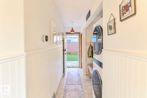 Hallway featuring wainscoting, tile flooring, and a glass-paneled exterior door - 3911 117 Street Nw, Edmonton, AB 