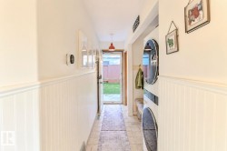 Hallway featuring wainscoting, tile flooring, and a glass-paneled exterior door - 