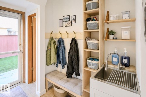 Mudroom featuring a built-in bench, wall-mounted coat hooks, integrated shelving, and a utility sink with a high-arc faucet - 3911 117 Street Nw, Edmonton, AB 