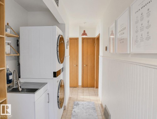 Stackable laundry appliances, integrated utility sink, wood-finish shelving, tile flooring, and wainscoting - 3911 117 Street Nw, Edmonton, AB 