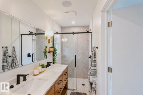 Dual vanity with white undermount sinks, wood-finish cabinetry, and matte black fixtures - 3911 117 Street Nw, Edmonton, AB 