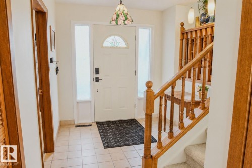 Entryway featuring a solid wood door with decorative glass, two sidelight windows, and tile flooring - 3911 117 Street Nw, Edmonton, AB 