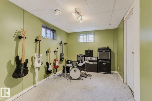 Carpeted room featuring light green paneling, drop ceiling with track lighting, and a window - 3911 117 Street Nw, Edmonton, AB 